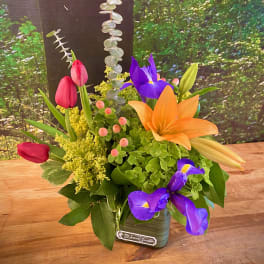 Colorful bouquet with tulips, iris, and lilies in a small vase