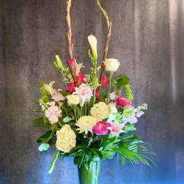 Tall mixed flower arrangement in a clear glass vase with pink, white, and cream blooms