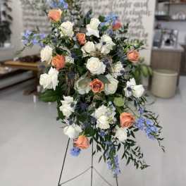 Standing floral spray with white and peach roses and blue accents