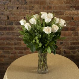 White roses in a clear glass vase on a table