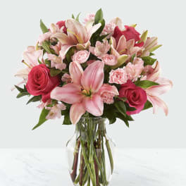 Pink lilies, roses, and carnations in a clear glass vase