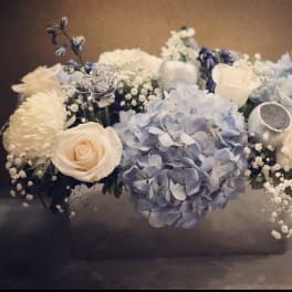 Blue hydrangeas and cream roses arranged in a low box
