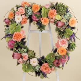 Heart-shaped floral wreath with roses and succulents on a stand