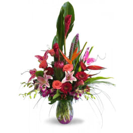 Tropical bouquet with pink lilies, roses, and orchids in a glass vase