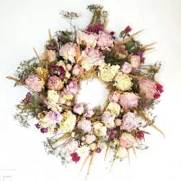 Dried floral wreath with pink and cream blooms on a white background