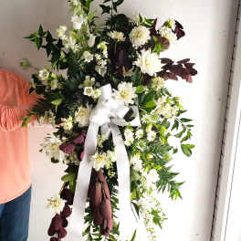 White floral wreath with a large white ribbon bow