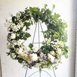 Large floral wreath of white and green flowers on a black stand