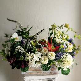 Mixed floral arrangement in a rustic wooden box with white, red, and purple blooms