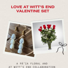 Valentine gift set with red rose bouquet in a glass vase and dangling teardrop bead earrings on a neutral background.