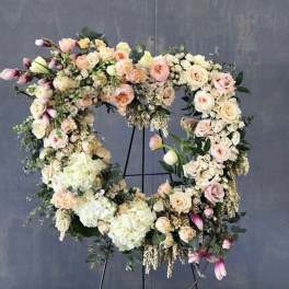 Large floral wreath of pastel roses and hydrangeas on a stand