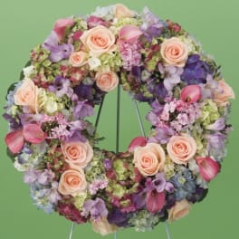 Circular floral wreath with pink roses and purple blooms on a stand