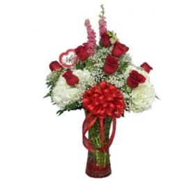 Red roses and white flowers in a glass vase with a red bow