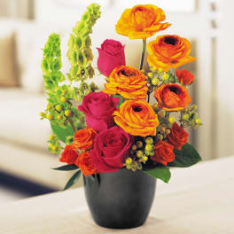 Orange ranunculus and pink roses in a black vase