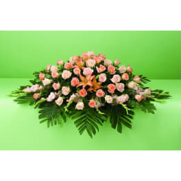 Low floral arrangement of pink roses and lilies on palm leaves