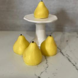 Four yellow pear-shaped objects on a white pedestal stand