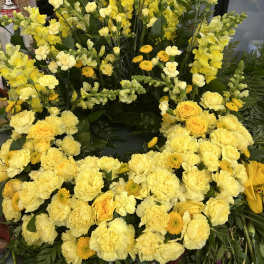 Large yellow floral wreath with roses, carnations, and snapdragons