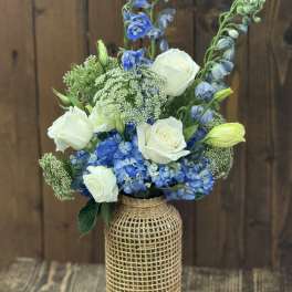 Blue and white floral arrangement in a woven vase