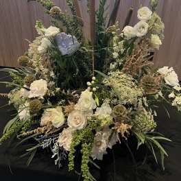 Large floral centerpiece with white roses and tall brown candles