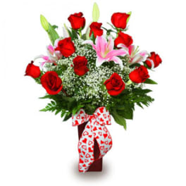 Bouquet of red roses and pink lilies in a vase with a heart ribbon