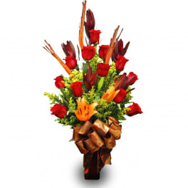Tall bouquet of red roses and orange lilies with a large brown ribbon bow
