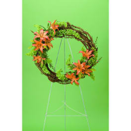 Circular floral wreath with orange lilies on a wire stand