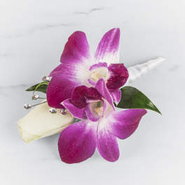 Pink orchids and a white rosebud boutonniere with jeweled accents and a wrapped stem.