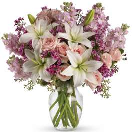 Pink roses and white lilies in a clear glass vase