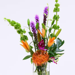 Tall mixed bouquet in a clear glass vase with orange and purple blooms
