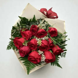 Bouquet of red roses wrapped in cream paper with a red ribbon