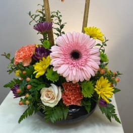Colorful flower arrangement with two decorative birds on a bamboo frame