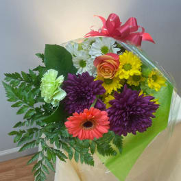 Mixed bouquet with daisies, a rose, gerbera, and chrysanthemums wrapped in clear plastic