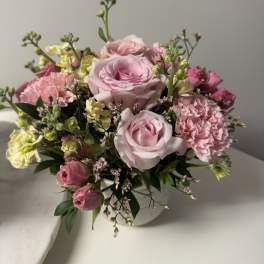 Pink roses and carnations arranged in a white vase