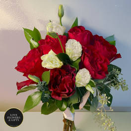 Hand-tied bouquet of red roses with white lisianthus buds and blooms, wrapped with a white ribbon.