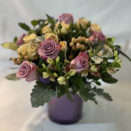 Lavender and cream rose bouquet in a purple vase