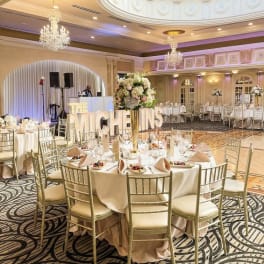 Floral centerpieces on round banquet tables in a decorated ballroom