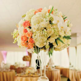 Tall floral centerpiece with white and peach blooms in a clear glass vase