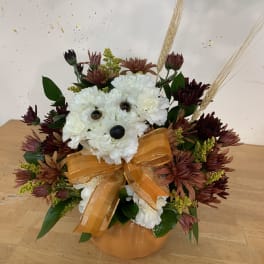 White flower bear arrangement with an orange bow in a pumpkin vase