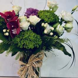 Bouquet of white roses, green hydrangeas, and magenta orchids in a glass vase