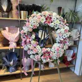 Heart-shaped floral wreath on an easel with pink and white flowers
