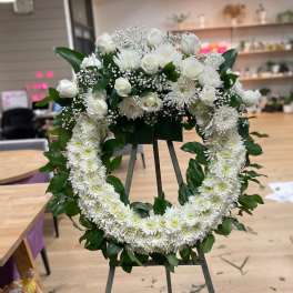 White floral wreath on an easel with roses and chrysanthemums