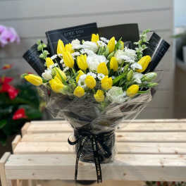 Bouquet of yellow tulips and white flowers wrapped in black paper
