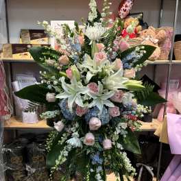 Large standing floral spray with white lilies, pink roses, and blue hydrangeas