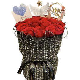 Red roses in a black woven gift wrap with a card and decorative toppers