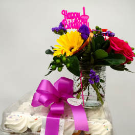 Birthday flower arrangement with cupcakes and a pink topper in a jar vase