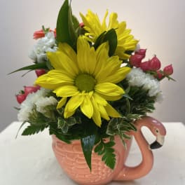 Yellow daisies and pink buds arranged in a flamingo mug