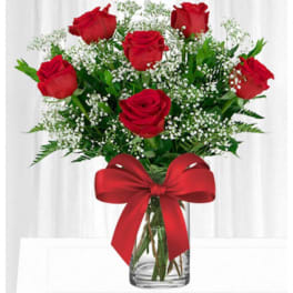 Bouquet of red roses with baby's breath in a clear glass vase and red ribbon