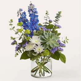 Blue and white flowers arranged in a clear glass vase with a succulent