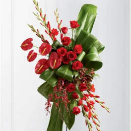 Red roses with anthuriums and tropical foliage on a stand