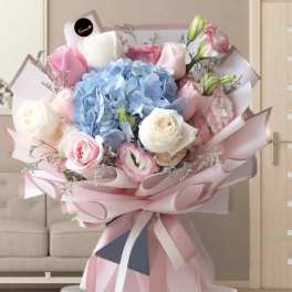 Bouquet of blue hydrangeas and pink-white roses wrapped in pale pink paper