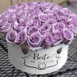 Lavender roses arranged in a round white hat box